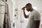 Young African man cutting his hair in his bathroom