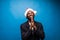 Young african man in santa hat pray for wish isolated on blue background