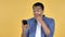 Young African Man in Shock while Using Smartphone, Yellow Background