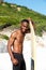 Young african man with surfboard standing at the beach