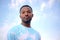 Young african man wearing tie and dye t-shirt on blue cloudy sky spiritual portrait