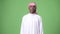 Young African man wearing traditional Muslim clothes against green background