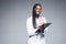 Young african medical intern doctor writing prescription on clipboard  on gray background