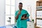 Young african physiotherapist man working at pain recovery clinic smiling happy and positive, thumb up doing excellent and