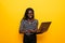 Young african positive woman using laptop and smiling isolated over yellow background
