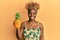 Young african woman with afro hair holding pineapple looking positive and happy standing and smiling with a confident smile