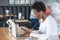 Young African woman with earphones, working on laptop in coffee shop