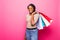 Young african woman holding shopping bags on pink backgrond