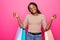 Young african woman holding shopping bags on pink backgrond