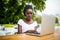 Young afro american black female freelancer working with digital tablet outdoors in cafe on a sunny day.