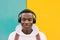 Young afro American black man listening music with wireless headphones while wearing a white sweatshirt and a backpack