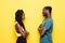 Young afro american couple offended standing face to face isolated on yellow background