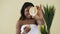 Young afro american woman holding lemon halves in hands over light background in spa centre. Healthy lifestyle, healthy