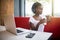 Young afro-american woman sitting behind laptop in cafe relaxing and drink milkshake