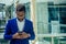 Young afro businessman in blue suit stands in office looks through big window at the city in airport terminal