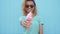 Young afro girl eating pink melting ice cream at blue wall background