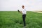 Young agronomist holds laptop in green wheat field. Agribusiness concept. agricultural engineer standing in a wheat field with a