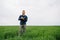 Young agronomist holds notebook in green wheat field. Agribusiness concept. agricultural engineer standing in a wheat field with a