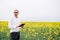 Young agronomist holds tablet in rape field. Agribusiness concept. agricultural engineer standing in a rape field with a tablet in