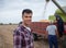 Young agronomist monitoring harvest of soy and two farmers working in background