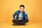Young Aisan man sitting and thinking something isolated on colore orange background