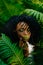 Young alluring african girl with green eyeshadows and lipstick is softly touching her face in the fern garden. Green