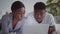 Young amazed african american married couple watching digital tv or online news on laptop, resting in bed, tracking shot