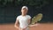 Young ambitious healthy lifestyle, portrait of tennis player girl with racket into hands on red court outdoors