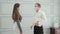 Young american business man in face mask and woman in face shield greeting with elbow bump at office.