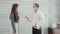 Young american business man in face mask and woman in face shield talking and greeting at office.