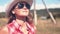 Young american cowgirl woman portrait outdoors. Beautiful natural woman takes off sun glasses touching cowboy hat.