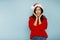 Young american woman wearing christmas red Santa Claus hat with hand near face, shocked and surprised. Christmas and New Year news