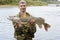 Young angler holds and showing big pike