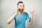 Young angry caucasian guy in blue t-shirt talk and scream on the phone, on light gray background