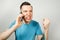 Young angry caucasian guy in blue t-shirt talk and scream on the phone, on light gray background