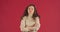 Young angry offended girl fashionable model sad girlfriend stands on red background demonstrates displeasure jealousy