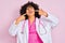 Young arab doctor woman with curly hair wearing stethoscope over isolated pink background smiling cheerful showing and pointing