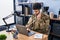 Young arab man army soldier using laptop talking on the telephone at office