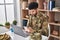 Young arab man army soldier using laptop using smartphone at home