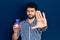 Young arab man with beard holding heart organ with open hand doing stop sign with serious and confident expression, defense