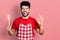 Young arab man with beard wearing baker uniform holding wooden spoon sticking tongue out happy with funny expression