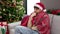 Young arab man feeling cold covered with blanket sitting on sofa by christmas tree at home