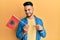 Young arab man holding albania flag smiling happy pointing with hand and finger