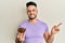 Young arab man holding raisins bowl smiling happy pointing with hand and finger to the side