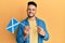 Young arab man holding scotland flag smiling happy pointing with hand and finger