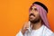 Young Arab man holding traditional beads against orange background