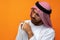 Young Arab man holding traditional beads against orange background