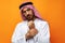 Young Arab man holding traditional beads against orange background