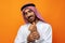 Young Arab man holding traditional beads against orange background