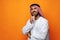 Young Arab man holding traditional beads against orange background